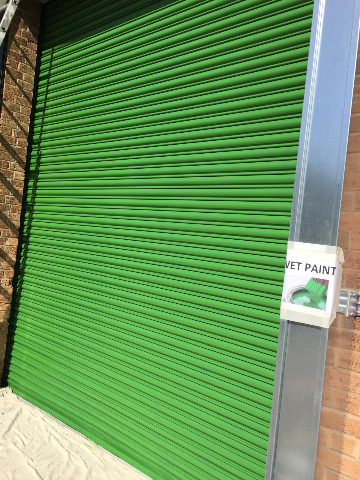 Industrial unit with bright green roller shutter and matching steel frame