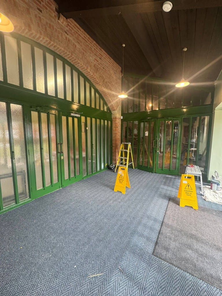 Interior church foyer with high-gloss green glass partition doors and brick arch