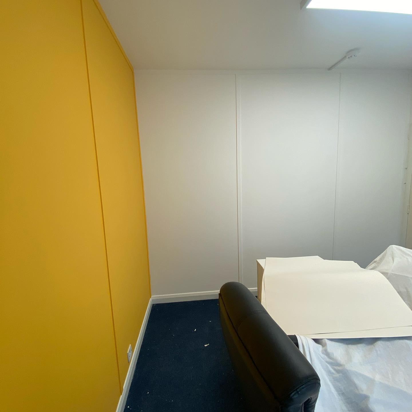 Office space with a bold yellow accent wall and crisp white trim