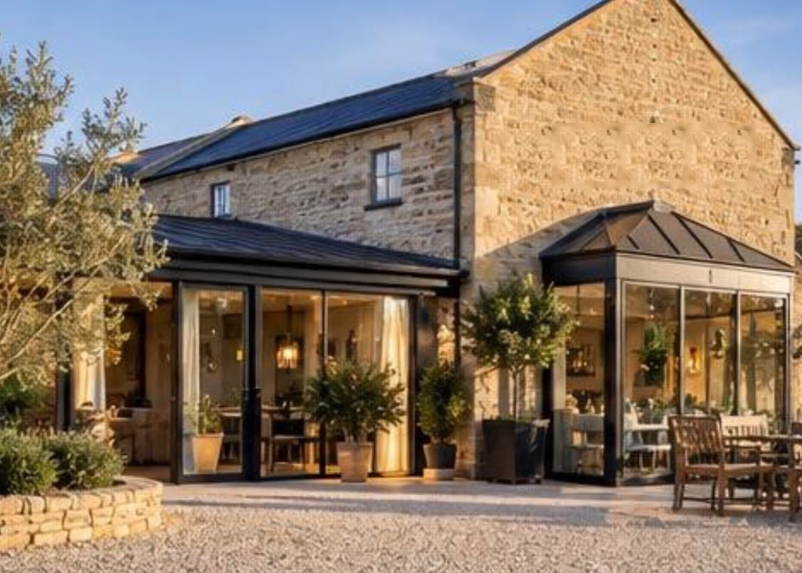 Stone-built café with a glazed orangery and outdoor seating on a gravel terrace