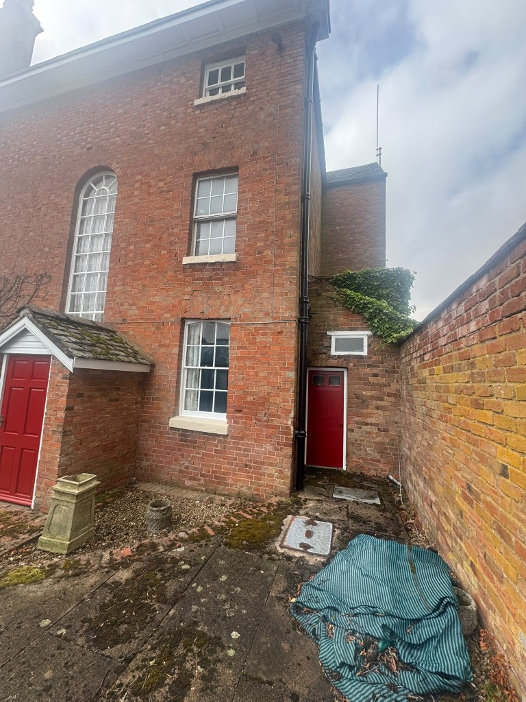 Farmhouse courtyard with freshly painted red entrance doors, white sash windows and arched window on red brick