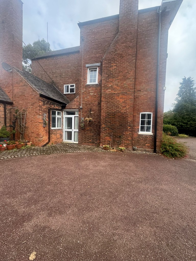 Rear courtyard of the farmhouse with white-painted windows and doors against historic red brick