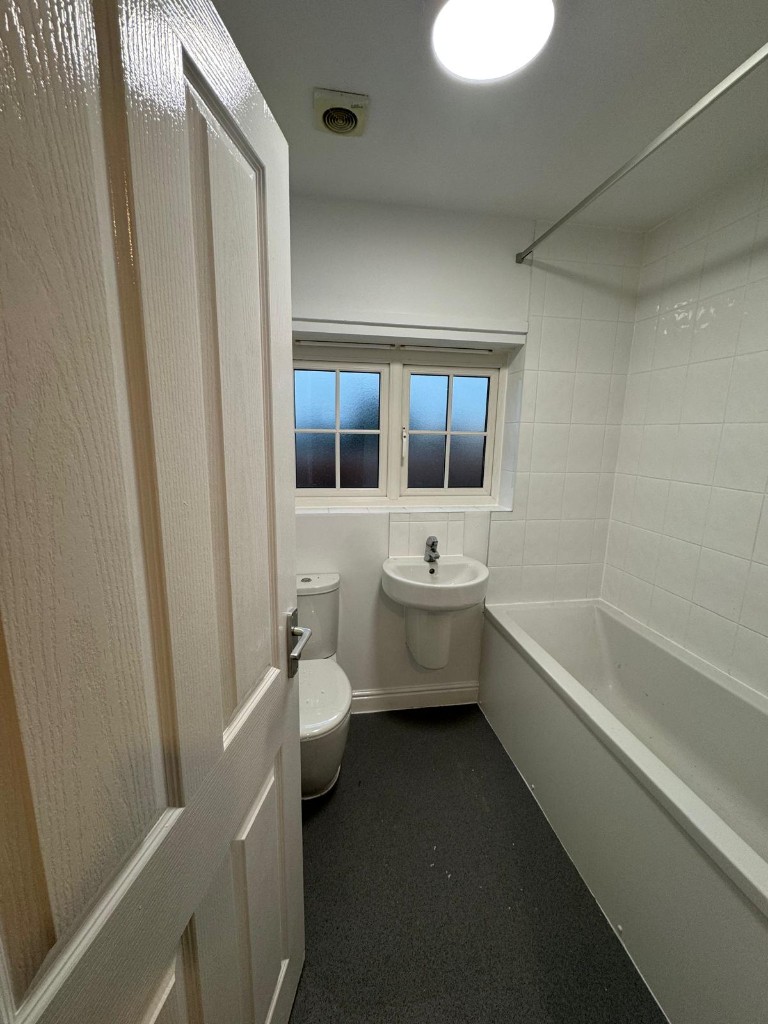 Repainted bathroom with white walls, tiles and dark vinyl floor in social housing stock