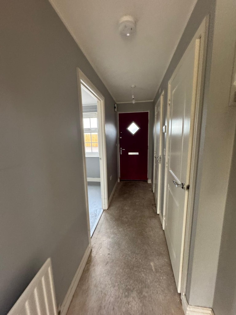 Repainted hallway with grey walls, white woodwork and burgundy front door ready for handover