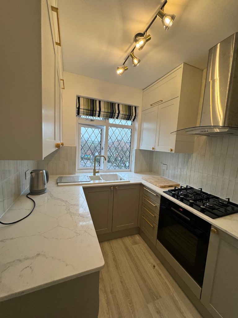Refurbished kitchen with marble-effect worktops and sage cabinetry in a social housing property