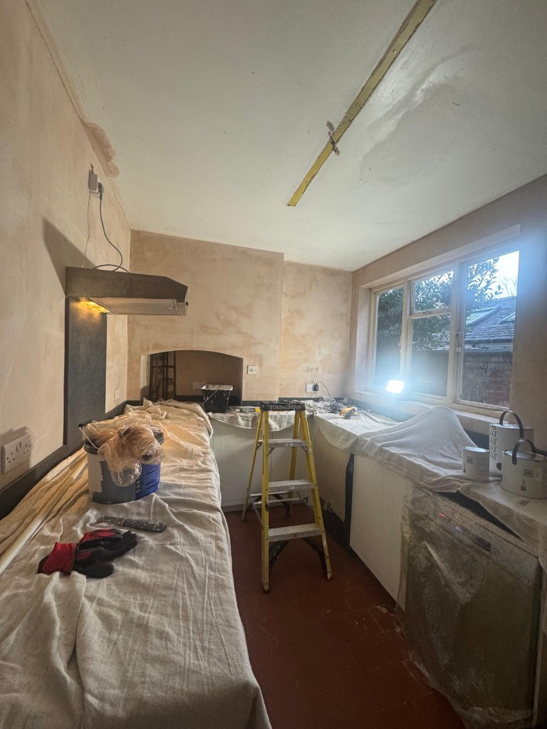Kitchen prepared for painting with protected worktops, ladder and trade materials