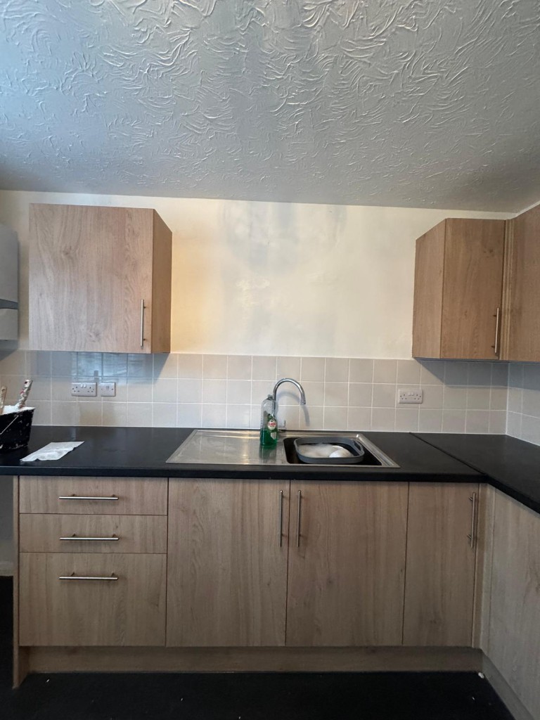 Kitchen with refreshed white walls, tiled splashback and wood-effect units